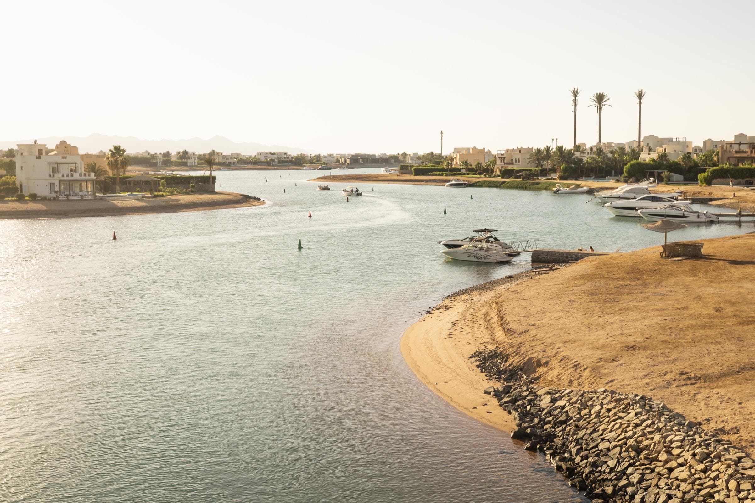 Golden afternoon light over a quiet lagoon with villas and moored boats in El Gouna